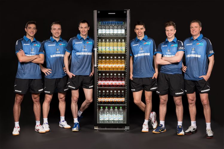 Ein Kühlschrank für Getränke in der Mitte ist sicherlich auch ein interessant gewähltes Motiv für ein Mannschaftsfoto. Wie hier vom Hauptsponsor der TTF Liebherr Ochsenhausen. Von links nach rechts: Hugo Calderano, Simon Gauzy, Stefan Fegerl, Jakub Dyjas, Vladimir Sidorenko und Trainer Dmitrij Mazunov. (©Verein)