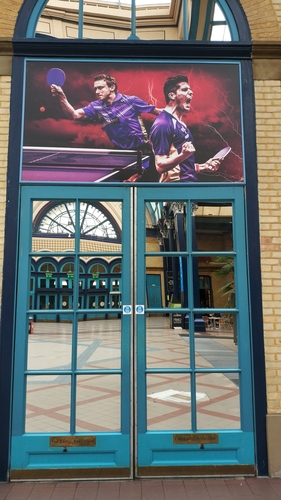 In der Szene ist er eine bekannte Größe: Schon im letzten Jahr sah man Alexander Flemmings Gesicht während der World Championship of Ping Pong auf Werbebannern vor der Halle und am Eingang des Ally Pally. Hier war er jetzt wieder abgebildet. (©Flemming) 