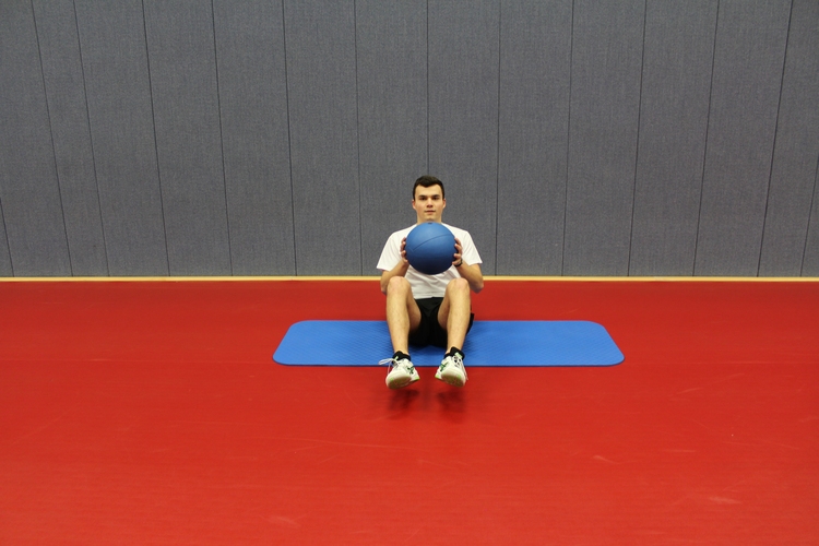 Übung 2 (Medizinball im Sitz): Die Beine sind vom Boden abgehoben. (©Schäbitz)